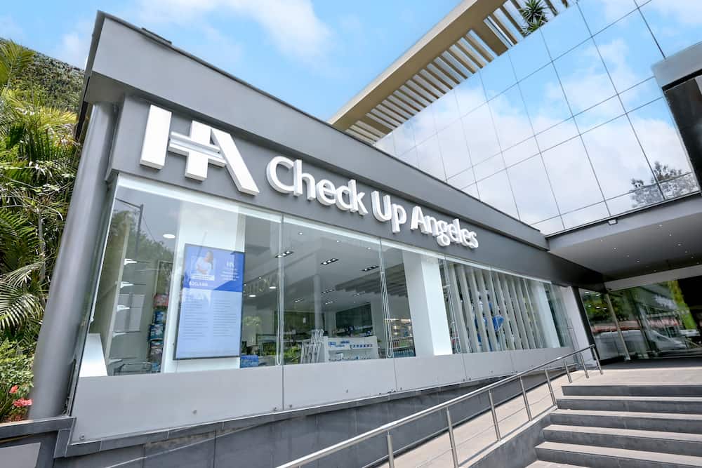 Fachada de color gris con cristales transparentes, barandales metálicos y logo del Hospital Angeles con letras blancas de Check up Angeles.