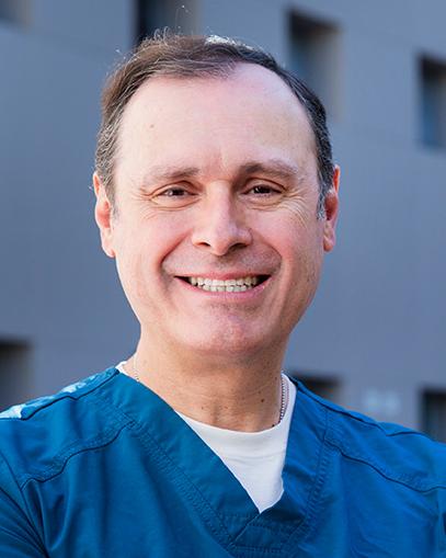 Es la foto de perfil de un ginecólogo y obstetra en Huixquilucan. Tiene el cabello café. Está sonriendo. Usa un uniforme médico azul.