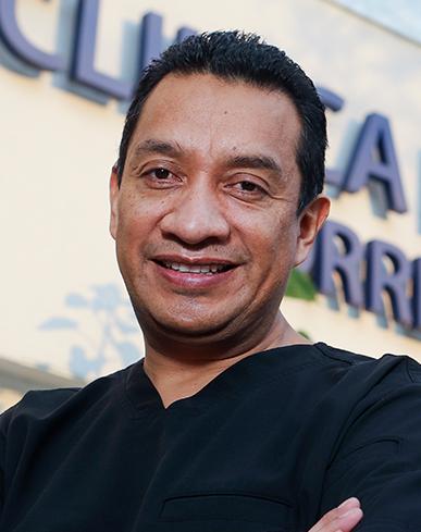 Es la foto de perfil de un Coloproctólogo especialista en gastrocirugía y en cirugía general en Ciudad de México de Hospital Angeles. El doctor tiene el cabello oscuro y corto, y está sonriendo. Viste un uniforme médico de color negro. El doctor brinda sus servicios en Hospital Angeles Clínica Londres y Lomas.