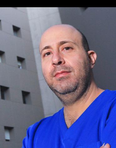 Es la foto de perfil de un artroscopista, ortopedista y traumatólogo en Huixquilucan de Hospital Angeles Lomas. Usa un uniforme médico con cuello V. Tiene barba. 