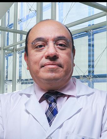 Es la foto de perfil de un artroscopista, ortopedista y traumatólogo en Huixquilucan de Hospital Angeles Lomas. Usa una bata blanca con camisa y corbata, el doctor usa lentes. 