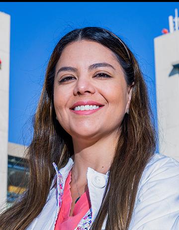 Es la foto de perfil de una pediatra en Huixquilucan de Hospital Angeles Lomas. Usa una bata blanca con una blusa rosa coral y está sonriendo.
