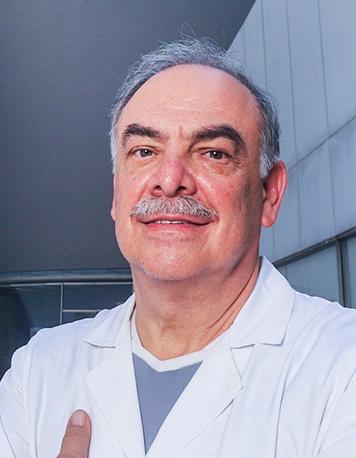 Es la foto de perfil de un anestesiólogo en Huixquilucan de Hospital Angeles Lomas. Usa una bata blanca, con un uniforme azul debajo, tiene el cabello canoso, y bigote.
