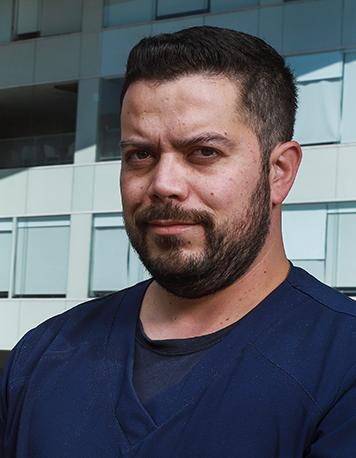 Es la foto de perfil de un artroscopista, ortopedista y traumatólogo en Ciudad de México de Hospital Angeles. Está vestido con un uniforme azul marino y playera azul de fondo, tiene barba y bigote. Nuestro especialista brinda sus servicios en hospital Angeles Acoxpa y Lindavista.