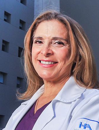 Es la foto de perfil de una ortodoncista en Huixquilucan de Hospital Angeles Lomas. Tiene el cabello rubio y con ondas, está sonriendo y tiene una bata blanca con blusa morada. 