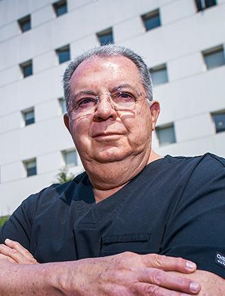 Es la foto de perfil de un cirujano pediátrico en Ciudad de México de Hospital Angeles Lindavista. Tiene el cabello canoso. Usa un uniforme médico azul oscuro. 