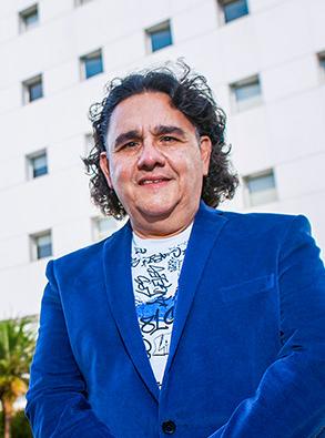 Es la foto de perfil de un cirujano general en Ciudad de México de Hospital Angeles Lindavista. Tiene el cabello negro. está sonriendo. Usa un saco color azul y una playera blanca con estampado.