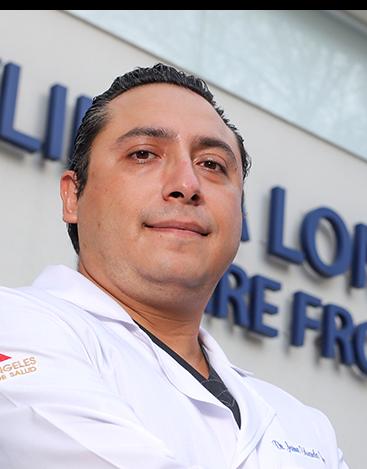 Es la foto de perfil de un cardiólogo intervencionista en Ciudad de México. Utiliza una bata blanca y de fondo se encuentra el hospital. El especialista brinda sus servicios en Hospital Angeles Clínica Londres y Lindavista.