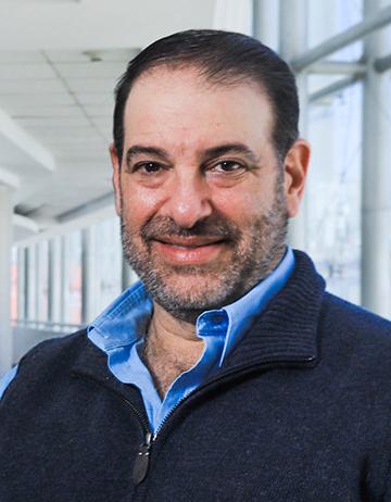 Es la foto de perfil de un ginecólogo y obstetra en Huixquilucan de Hospital Angeles Lomas. Usa un suéter negro con una camisa azul cielo.