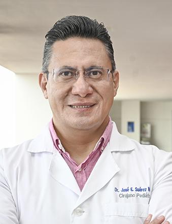 Es la foto de perfil de un pediatra especialista en cirugía pediátrica en León de Hospital Angeles León. Utiliza una bata blanca con camisa rosa, tiene lentes y está sonriendo. 