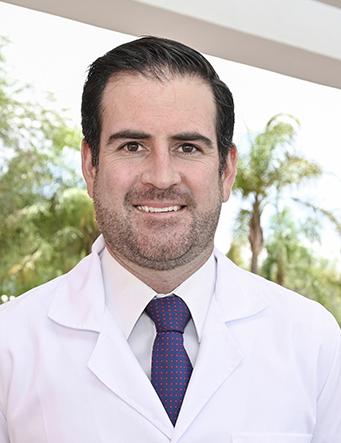 Es la foto de perfil de un otorrinolaringólogo en León de Hospital Angeles León. Utiliza una bata blanca, tiene una camisa blanca y una corbata azul marino.