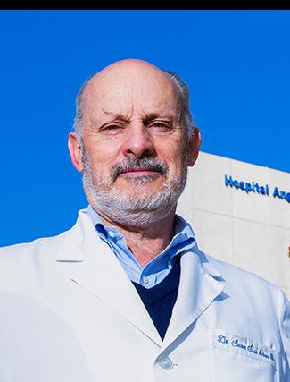 Es la foto de perfil de un oftalmólogo en Huixquilucan de Hospital Angeles Lomas. Usa una bata blanca con una camisa azul claro, tiene barba y bigote canoso.