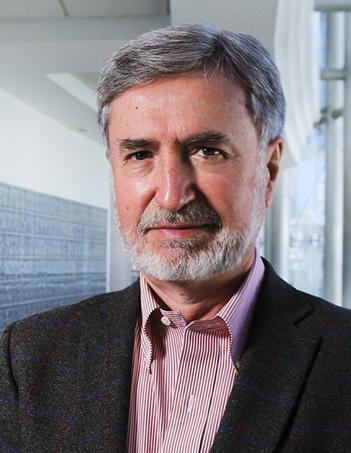 Es la foto de perfil de un cirujano plástico en Huixquilucan de Hospital Angeles Lomas. Usa un saco negro con una camisa roja con lineas blancas. Tiene el cabello canoso, barba y bigote.