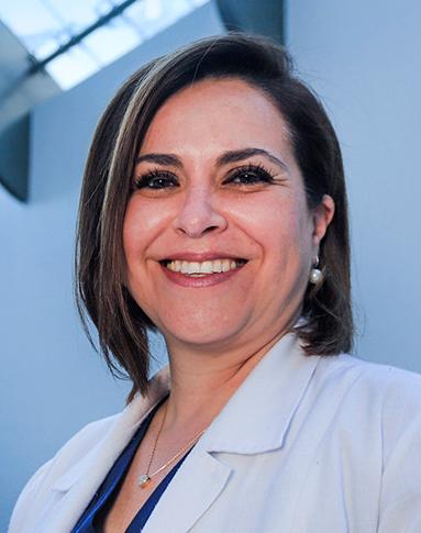 Es la foto de perfil de una psiquiatra en Huixquilucan de Hospital Angeles Lomas. Usa una bata blanca con una blusa azul marino, tiene un collar plata y aretes.