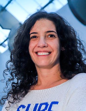 Es la foto de perfil de una ginecóloga en Huixquilucan de Hospital Angeles Lomas. Usa un suéter gris con letras azules, la doctora es de cabello rizado y oscuro.