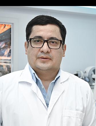 Es la foto de perfil de un radiólogo en Ciudad Juárez de Hospital Angeles Ciudad Juárez. Utiliza una bata blanca y una camisa azul claro, tiene lentes.