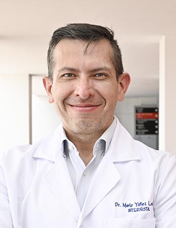 Es la foto de perfil de un internista en León de Hospital Angeles León. Utiliza una bata blanca con una camisa blanca, el doctor está sonriendo, es de tez blanca y cabello castaño.