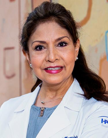 Es la foto de perfil de una pediatra en Ciudad de México de Hospital Angeles Lindavista. Tiene el cabello largo y café oscuro. Está sonriendo. Usa una bata blanca, una blusa azul claro y joyeria plata.