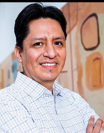 Es la foto de perfil de un cirujano neurológico en Ciudad de México de Hospital Angeles Lindavista. Tiene el cabello negro. Está sonriendo y tiene los brazos cruzados. Usa una camisa blanca de cuadros.