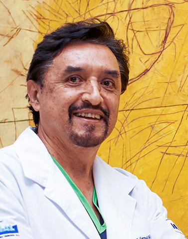 Es la foto de perfil de un ortopedista y traumatólogo en Ciudad de México de Hospital Angeles Lindavista. Tiene el cabello y barba negra. Está sonriendo. Usa una bata blanca y un uniforme médico verde.