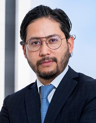 Es la foto de perfil de un gastroenterólogo en Ciudad de México de Hospital Angeles Roma. Usa un saco azul marino con camisa blanca y corbata azul claro. Tien eel cabello y barba negro. Usa lentes.