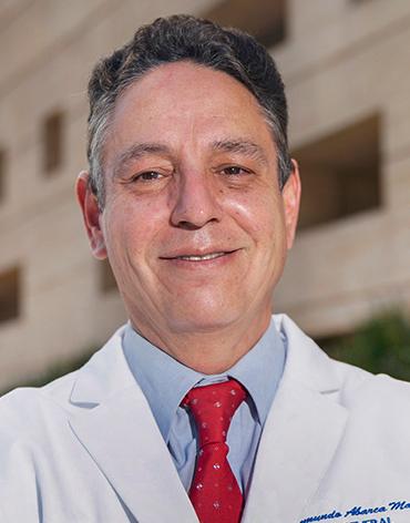 Es la foto de perfil de un cirujano general en Ciudad de México de Hospital Angeles. Usa una bata blanca con camisa azul y corbata roja.