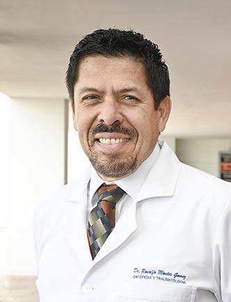 Es la foto de perfil de un ortopedista y traumatólogo en León de Hospital Angeles León. Tiene el cabello, barba y bigote negro. Usa una bata blanca junto con una corbata negra con estampado