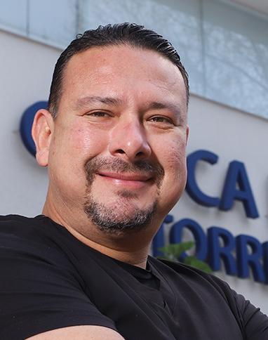 Es la foto de perfil de un ortopedista y traumatólogo en Ciudad de México de Hospital Angeles Universidad. Usa camisa negra. Tiene el cabello y barba negra. Está sonriendo ligeramente.
