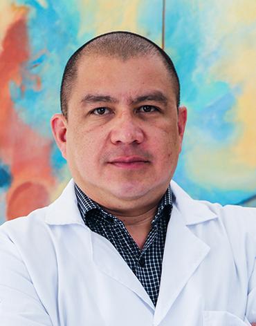 Es la foto de perfil de un cirujano general en Tampico de Hospital Angeles Tampico. Usa una bata blanca y una camisa verde oscuro.