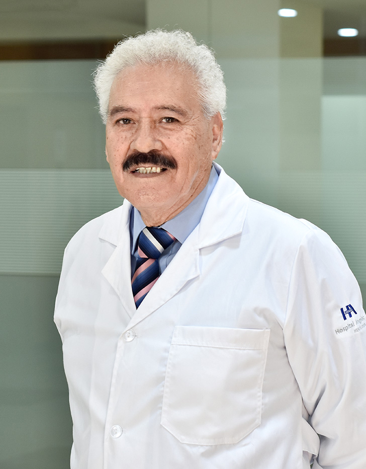 Es la foto de perfil de un médico general en Ciudad de México de Hospital Angeles Mocel. Usa una bata blanca y una camisa azul claro con una corbata azul oscuro. Tiene el cabello blanco y el bigote café.