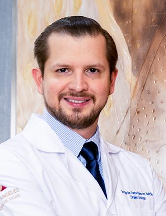 Es la foto de perfil de un urólogo en León de Hospital Angeles León. Utiliza una bata blanca, camisa azul claro, corbata azul marino y tiene barba.