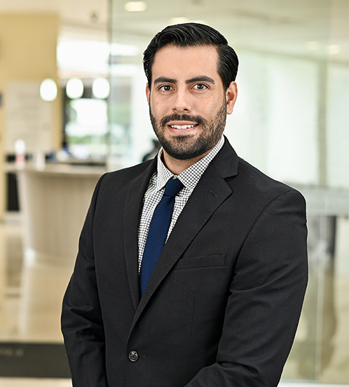 Es la foto de perfil de un cirujano neurológico en Ciudad de México de Hospital Angeles Acoxpa. Usa un saco olor negro, una camisa blanca con cuadros y una corbata azul. Tiene el cabello y barba negro.