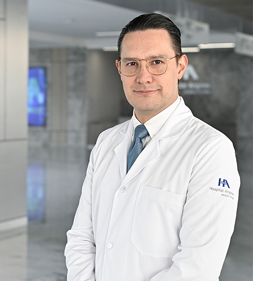 Es la foto de perfil de un radiólogo e imagenólogo en Querétaro de Hospital Angeles Centro Sur. Usa una bata y camisa color blanco, con una corbata color azul eléctrico. Tiene el cabello negro y usa lentes. No tiene barba.