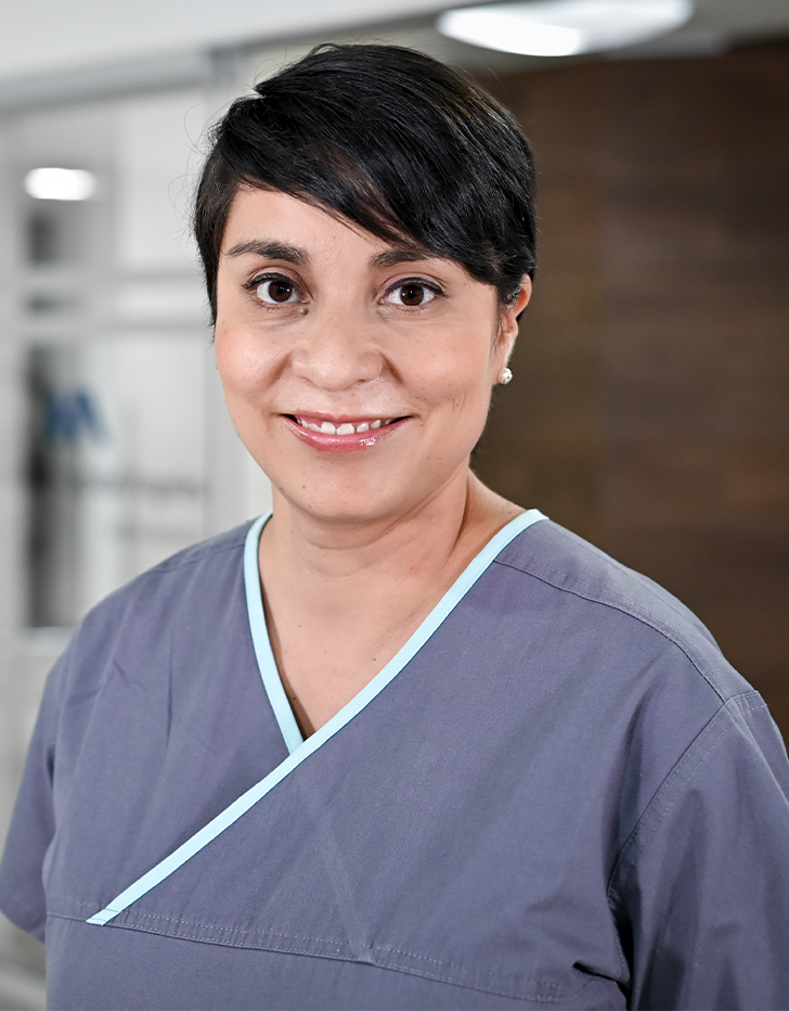 Es la foto de perfil de una ginecóloga, obstetra y especialista en biología de reproducción en Ciudad de México de Hospital Angeles Santa Mónica. Usa un uniforme médico gris. Tiene el cabello corto negro y está sonriendo.