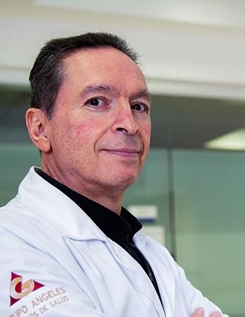 Es la foto de perfil de un ortopedista y traumatólogo en Huixquilucan. Tiene el cabello negro. Está sonriendo y tiene los brazos cruzados. Usa una bata blanca y camisa negra.