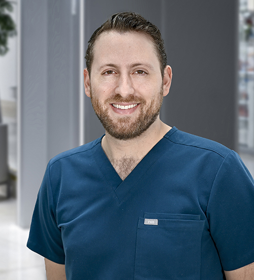 Es la foto de perfil de un otorrinolaringólogo en Huixquilucan. Tiene el cabello y barba café. Usa una bata blanca. Está sonriendo.