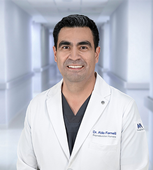 Es la foto de perfil de un ginecólogo y obstetra y biologo de reproducción de Hospital Angeles Ciudad Juárez. Usa una bata blanca, tiene cejas pobladas y está sonriendo. 