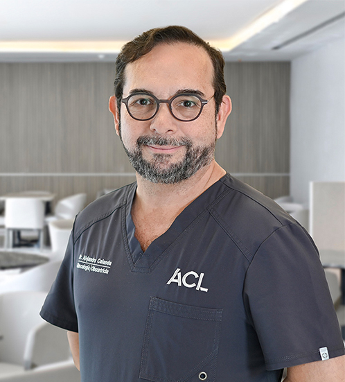 Es la foto de perfil de un ginecólogo y obstetra en San Pedro Garza de Hospital Angeles Valle Oriente. Usa un uniforme médico color azul. Tiene el cabello y barba café oscuro. Tiene los brazos cruzados.