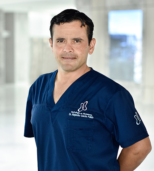 Es la foto de perfil de un nefrólogo en Querétaro de Hospital Angeles Centro Sur. Es de tez morena, usa un uniforme azul marino y tiene las manos cruzadas por detrás de la espalda.