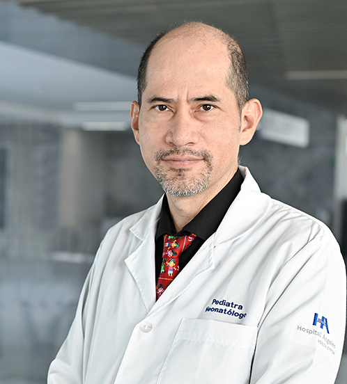 Es la foto de perfil de un pediatra en Querétaro de Hospital Angeles Centro Sur. Usa bata blanca con una camisa negra y corbata azul, está sonriendo.