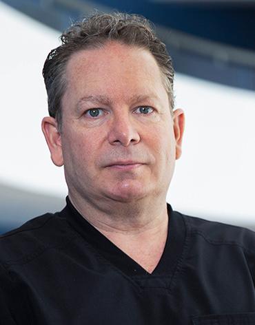 Es la foto de perfil de un dermatólogo en Huixquilucan. Tiene el cabello café. Usa un uniforme médico negro.