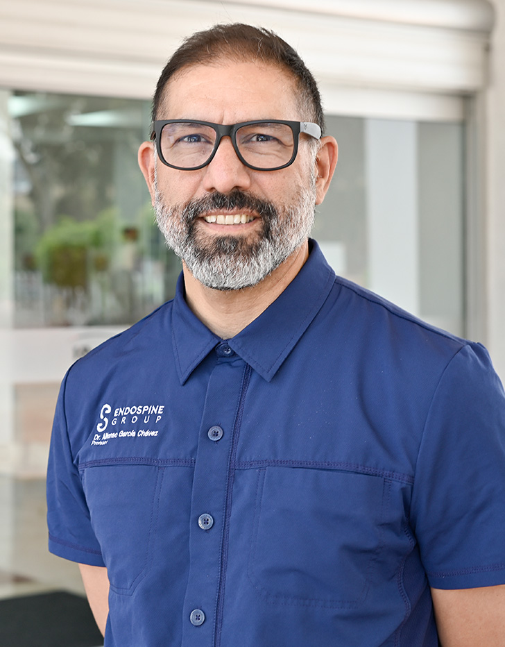 Es la foto de perfil de un ortopedista y traumatólogo en Tijuana de Hospital Angeles Tijuana. Usa un saco negro con cuadros y lentes. Tiene el cabello negro y barba negro con gris.
