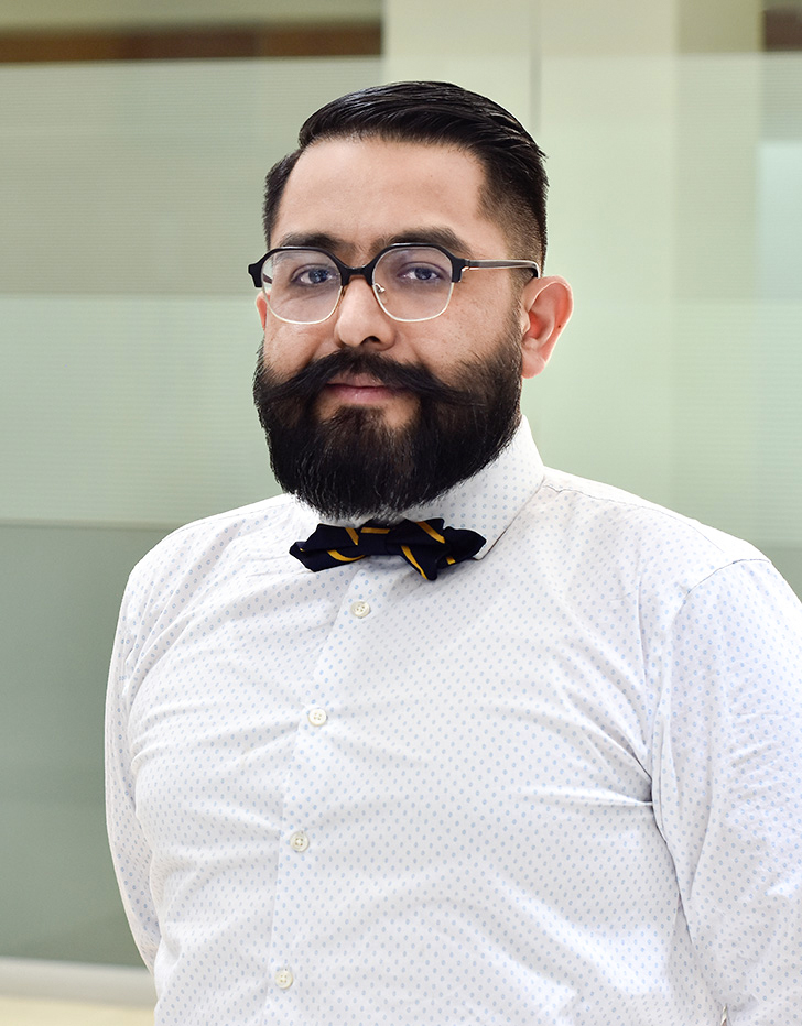 Es la foto de perfil de un psiquiatra infantil en Ciudad de México de Hospital Angeles Mocel. Usa una camisa blanca con puntitos color azules. Trae puesto un moño de rayas color amarillo y negro. Tiene el cabello y barba negro.