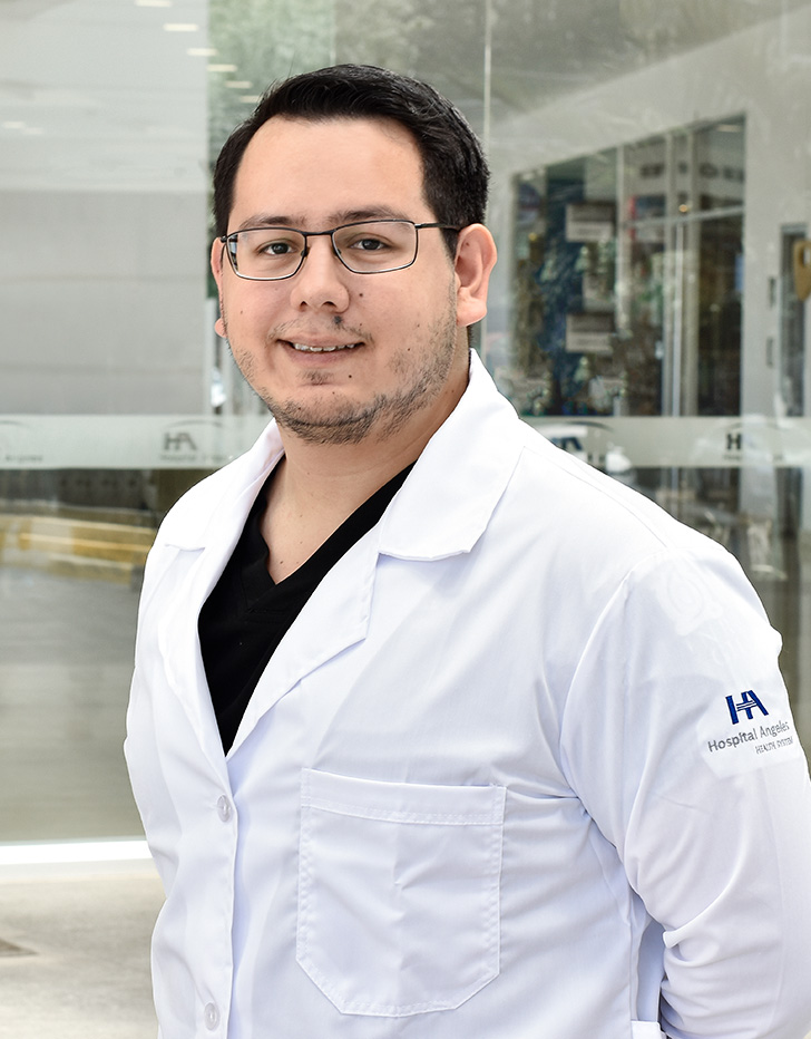 Es la foto de perfil de un ortopedista y traumatólogo pediátrico en Ciudad de México de Hospital Angeles Acoxpa. Usa una bata blanca y un uniforme médico color negro. Tiene el cabello color negro. Tiene poca barba y bigote. Usa lentes.