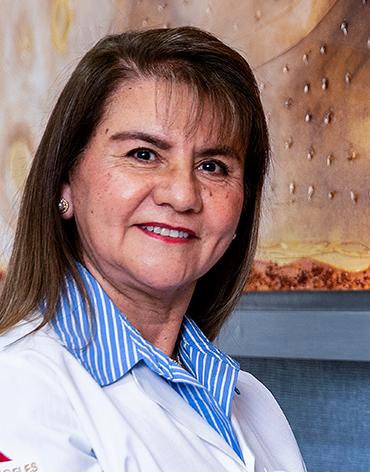 Es la foto de perfil de una psiquiatra infantil en León de Hospital Angeles León. Usa bata blanca con camisa azul y rayas verticales blancas.