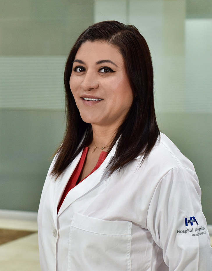 Es la foto de perfil de una anestesióloga en Ciudad de México de Hospital Angeles Mocel. Usa una bata blanca con una blusa naranja. Tiene el cabello color café oscuro y corto. Se encuentra de perfil.