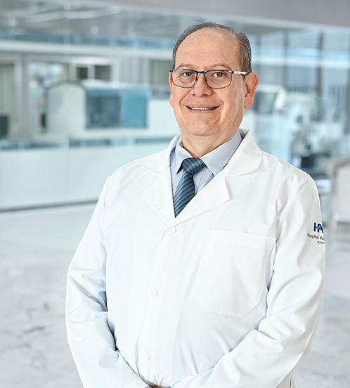 Es la foto de perfil de un otorrinolaringólogo en Guadalajara de Hospital Angeles Del Carmen. Utiliza una bata blanca, una camisa lila y una corbata azul marino.