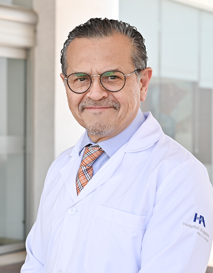 Es la foto de perfil de un urólogo en Tijuana de Hospital Angeles Tijuana. Usa una bata blanca, lentes y una corbata roja. Tiene bigote y está sonriendo.