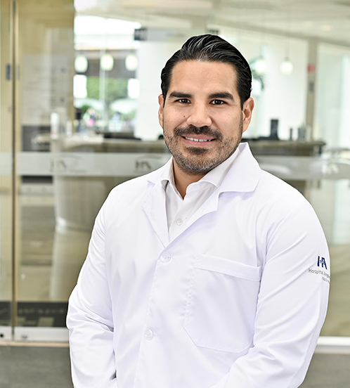 Es la foto de perfil de un cirujano general en Ciudad de México de Hospital Angeles Acoxpa. Usa una bata y camisa color blanco. Tiene el cabello y barba razurada color negro.