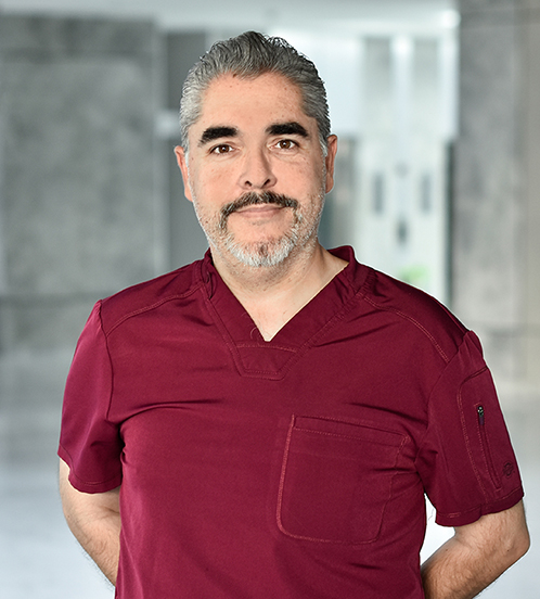 Es la foto de perfil de un cirujano general en Querétaro de Hospital Angeles Centro Sur. Usa un uniforme vino, tiene cejas pobladas, barba y bigote y cabello canoso.